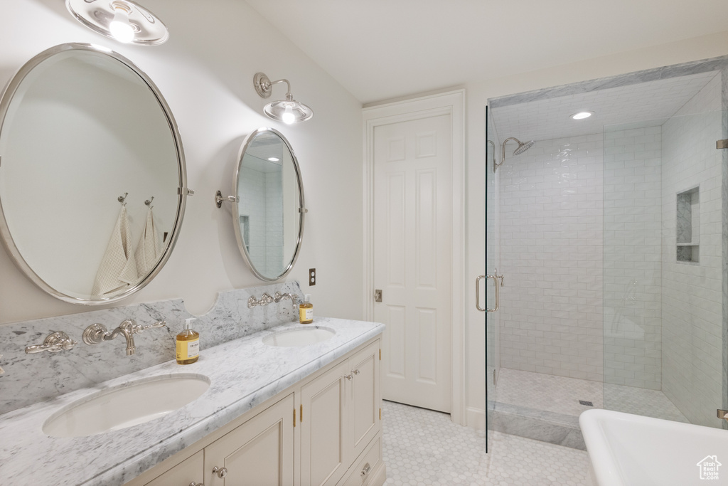 Full bathroom featuring a stall shower, double vanity, a freestanding tub, and tile patterned flooring
