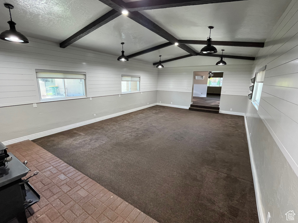 Unfurnished living room with baseboards, wooden walls, dark carpet, and a textured ceiling