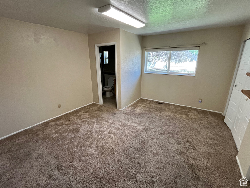 Unfurnished bedroom with carpet floors, baseboards, and a textured ceiling