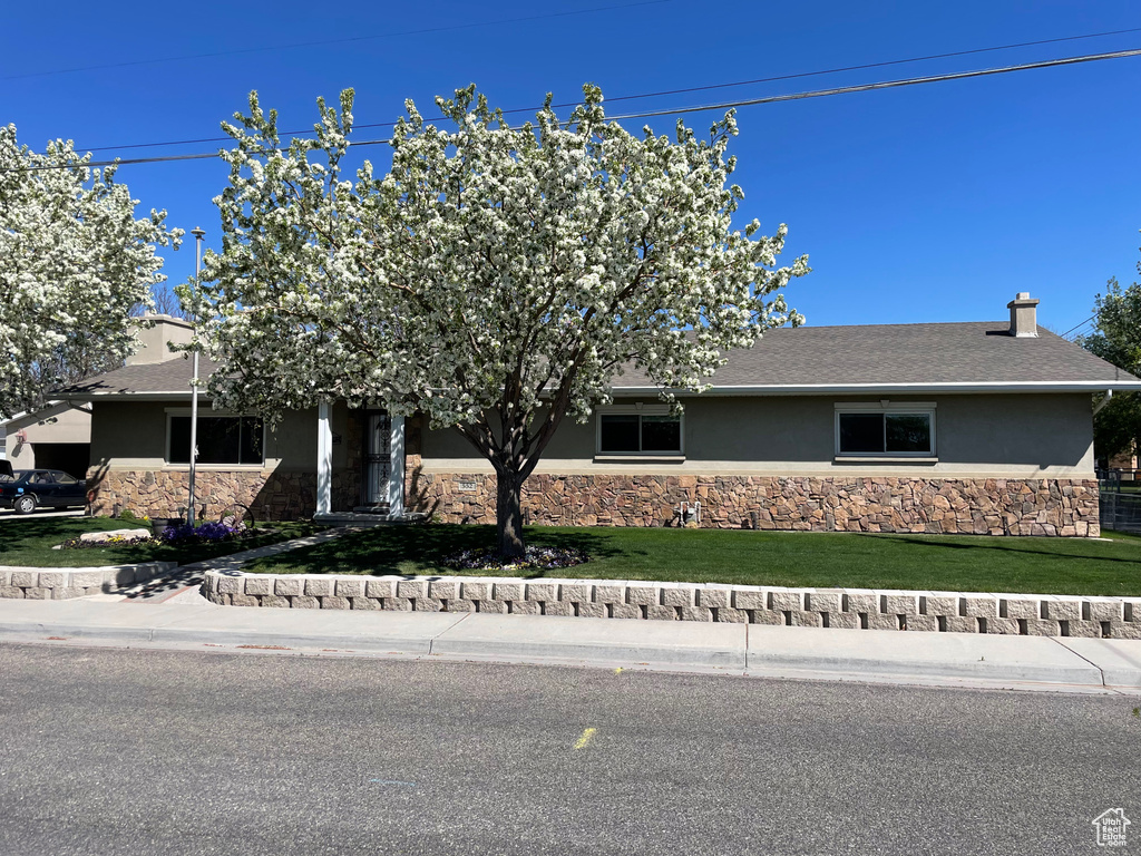 View of front of house with stone siding, stucco siding, and a front yard