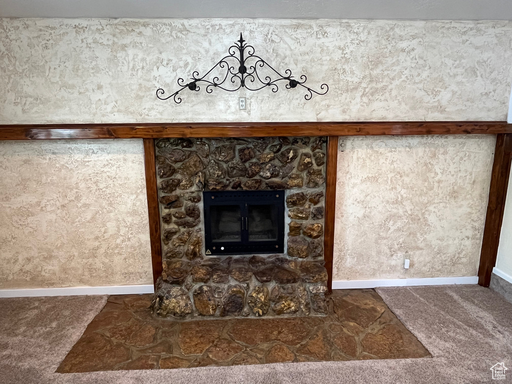 Detailed view of carpet floors, baseboards, and a stone fireplace