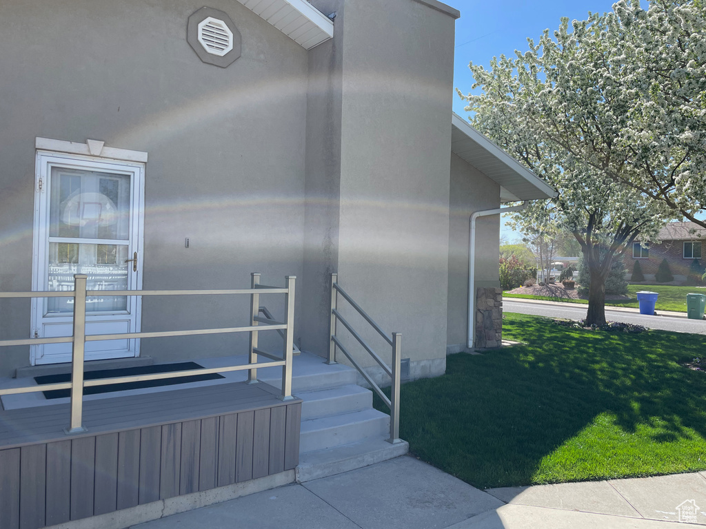 Property entrance with stucco siding and a lawn