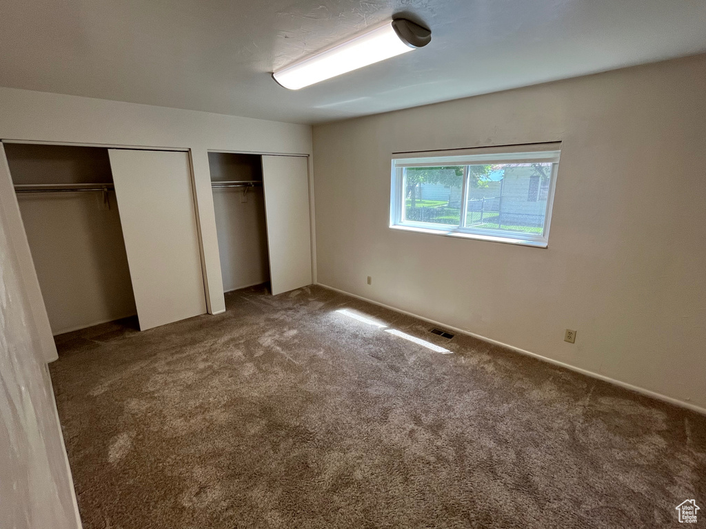 Unfurnished bedroom featuring two closets and carpet flooring