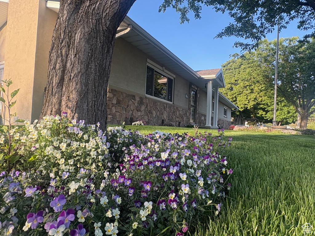View of side of property featuring stucco siding, stone siding, and a lawn