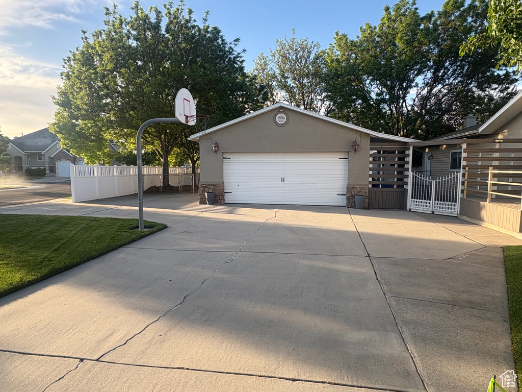 View of front of house featuring driveway, stucco siding, an attached garage, and stone siding