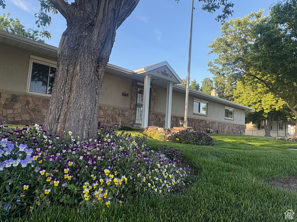View of home\'s exterior with stone siding, stucco siding, and a yard
