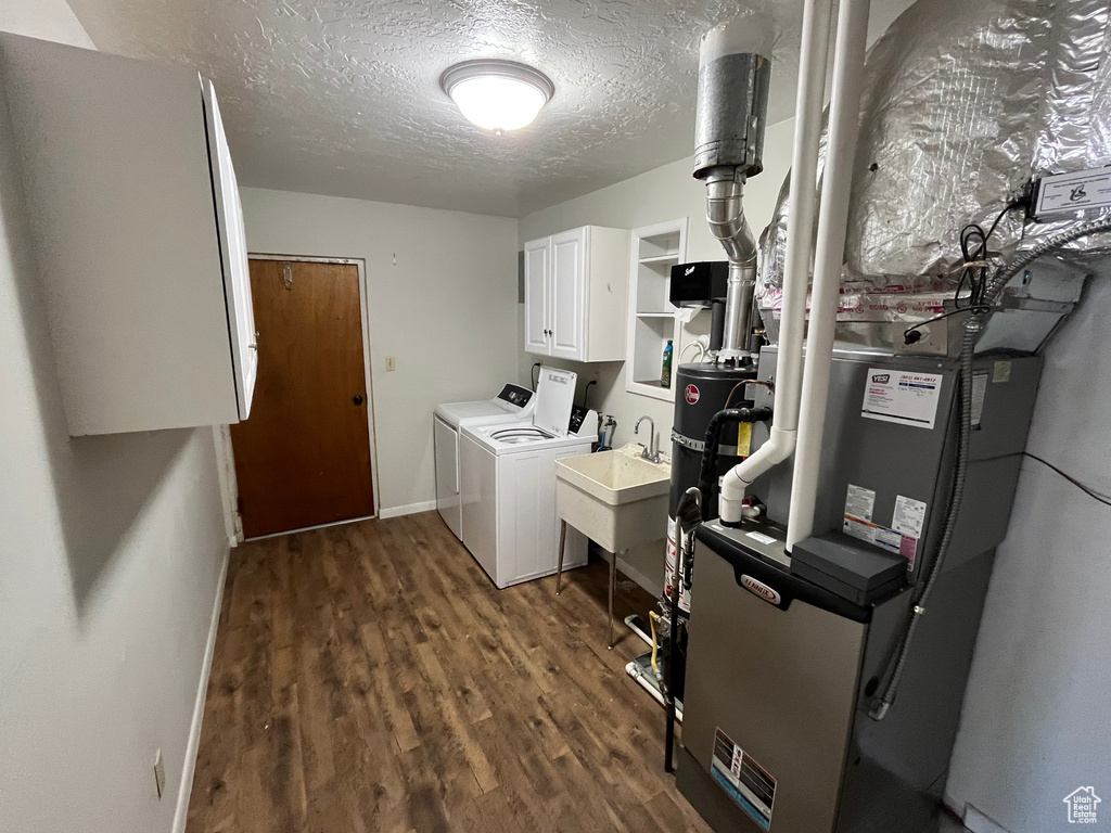 Laundry room with separate washer and dryer, cabinet space, dark wood-style flooring, a textured ceiling, and baseboards