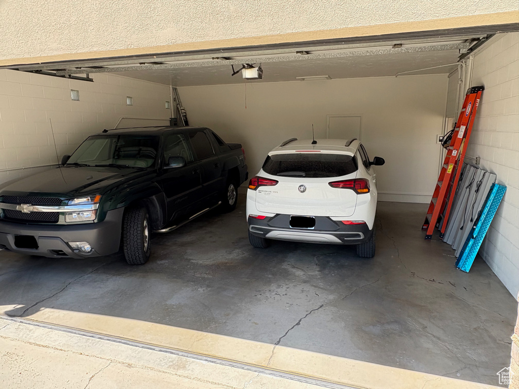 Garage featuring a garage door opener and concrete block wall