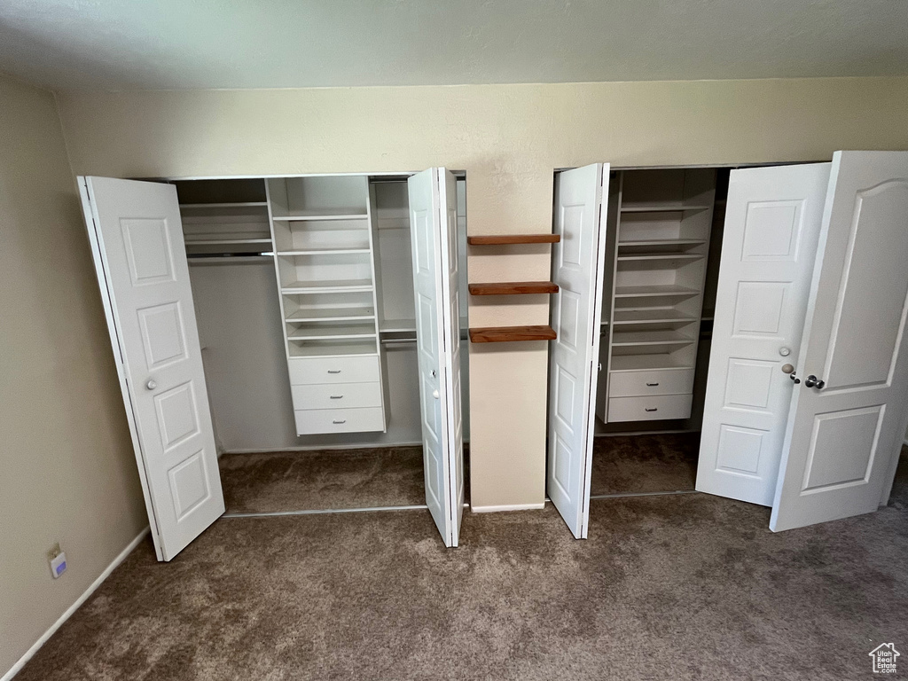 Unfurnished bedroom with two closets and dark colored carpet