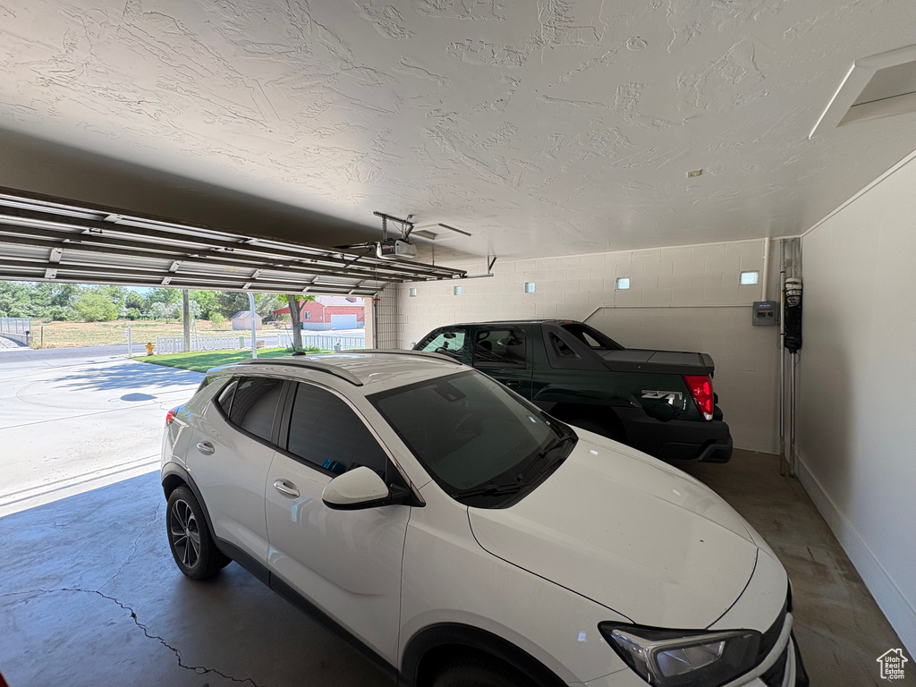 Garage featuring a garage door opener, concrete block wall, and baseboards