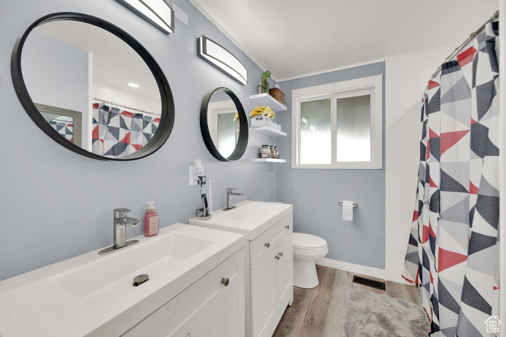 Full bath featuring wood finished floors, vanity, toilet, a shower with shower curtain, and baseboards