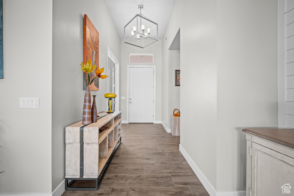 Hall featuring a chandelier, dark wood-type flooring, and baseboards