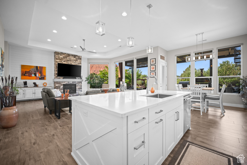 Kitchen featuring a ceiling fan, a sink, recessed lighting, a stone fireplace, and dark wood-type flooring