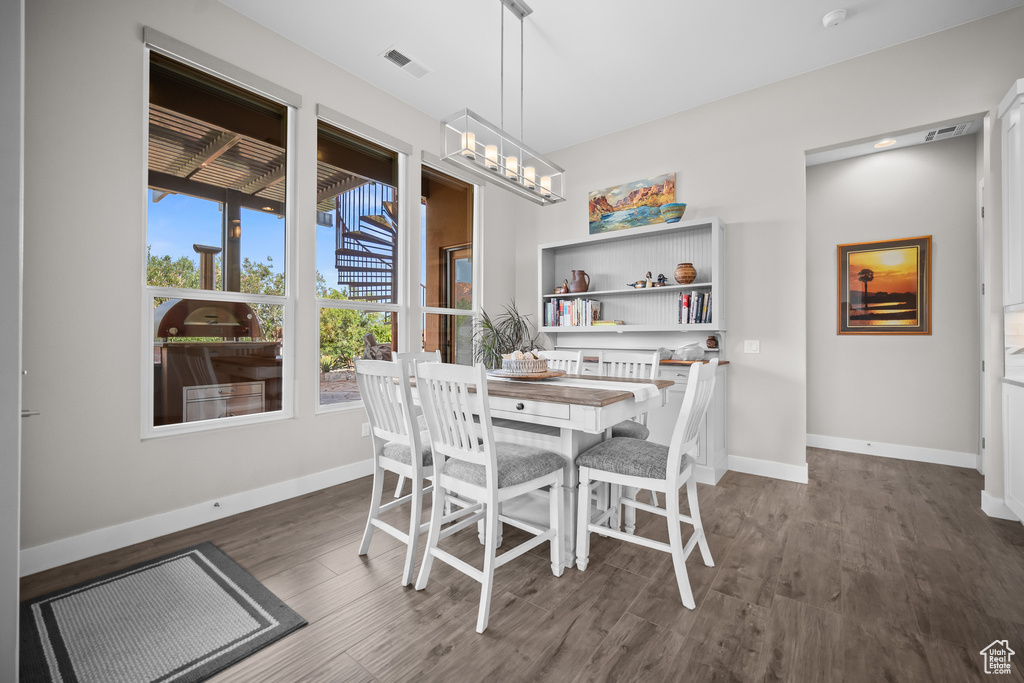 Dining room featuring dark wood-type flooring, baseboards, and a chandelier
