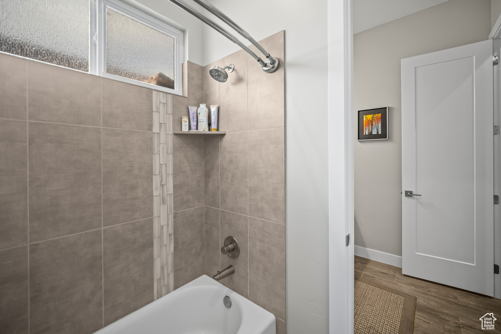 Full bath with shower / bath combination, wood finished floors, and baseboards