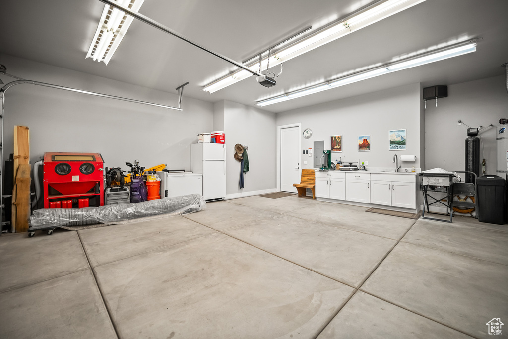 Garage with freestanding refrigerator, a sink, and a garage door opener