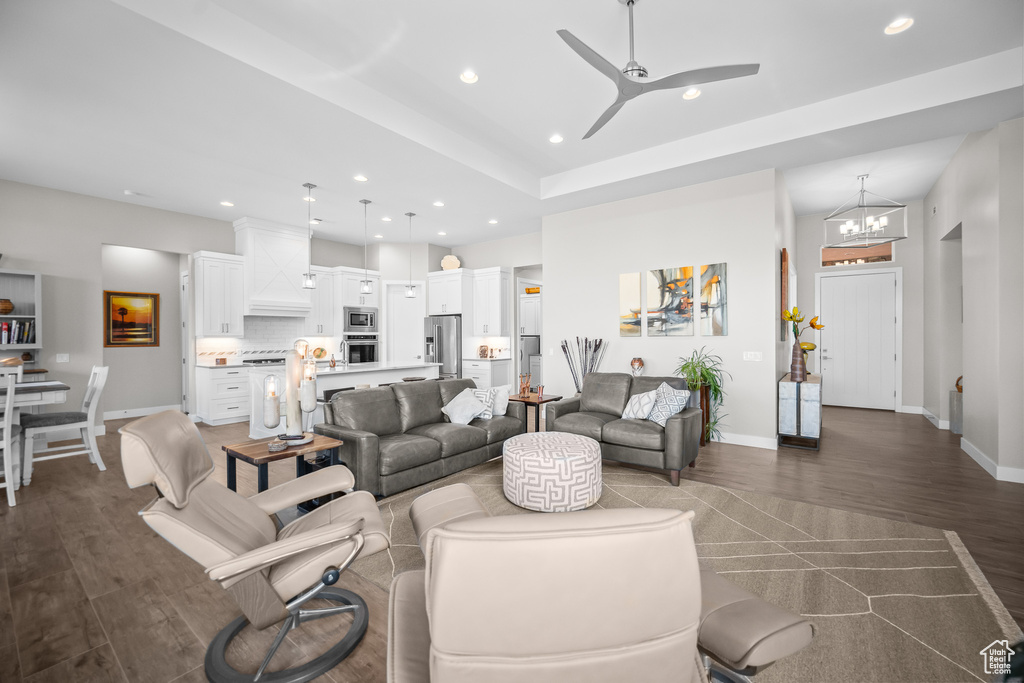 Living room featuring dark wood-style flooring, recessed lighting, a chandelier, baseboards, and ceiling fan
