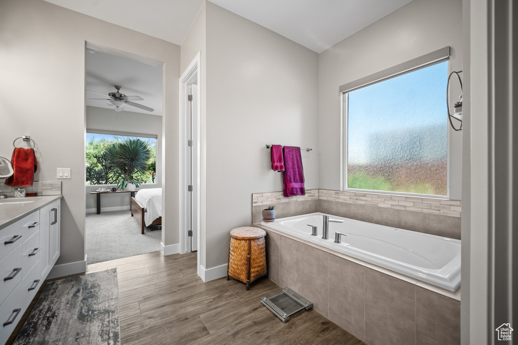 Full bath featuring connected bathroom, a garden tub, vanity, ceiling fan, and wood finished floors