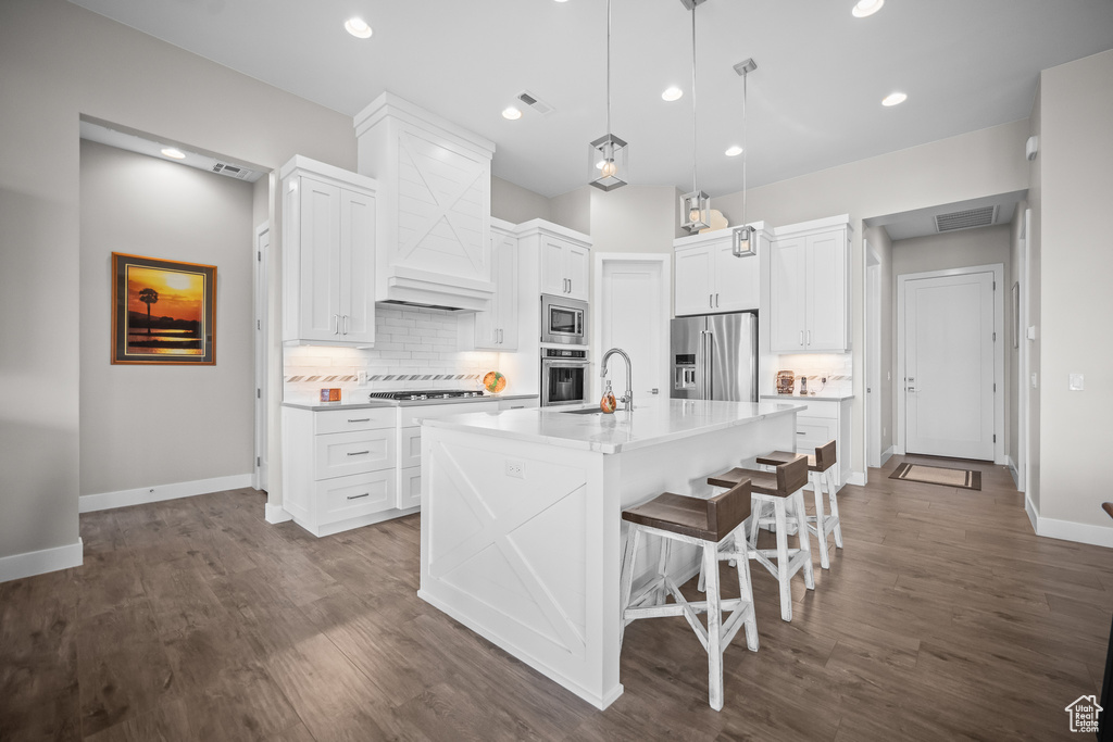 Kitchen featuring appliances with stainless steel finishes, a sink, baseboards, backsplash, and dark wood finished floors