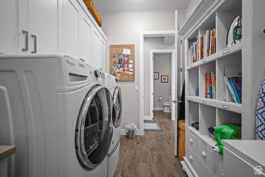Laundry room with cabinet space, separate washer and dryer, dark wood-type flooring, and baseboards