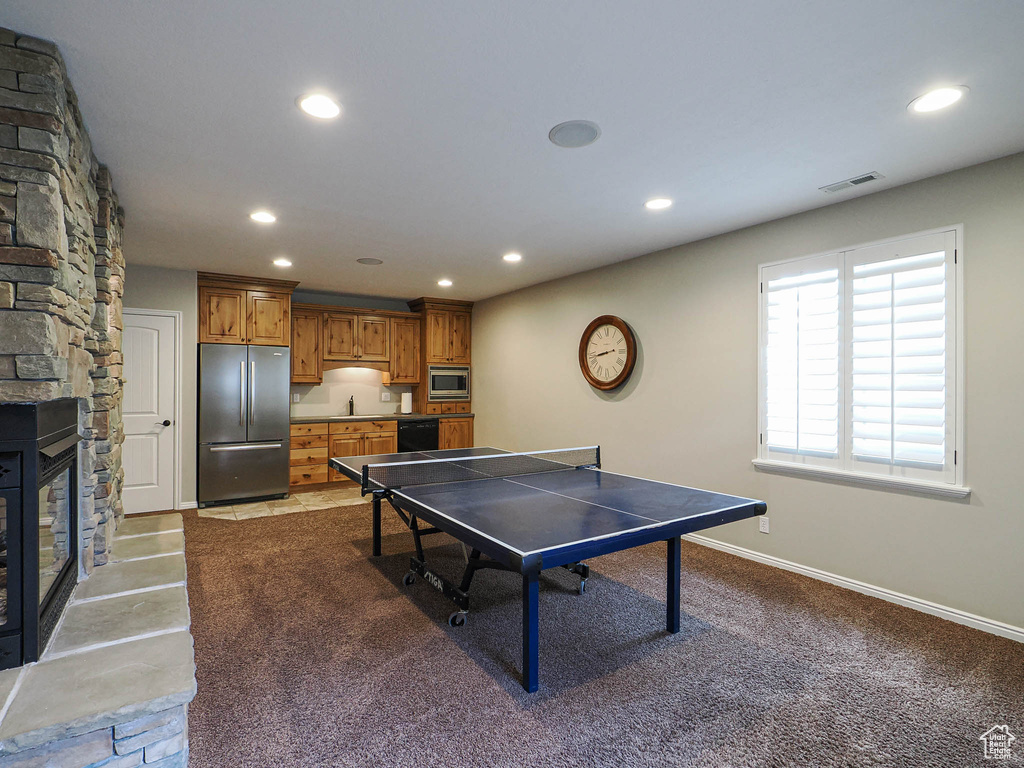 Recreation room with recessed lighting, a stone fireplace, baseboards, and carpet flooring
