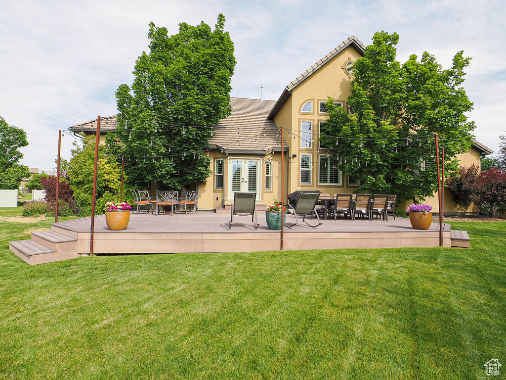 Rear view of house featuring a tiled roof, a deck, stucco siding, a yard, and outdoor dining space