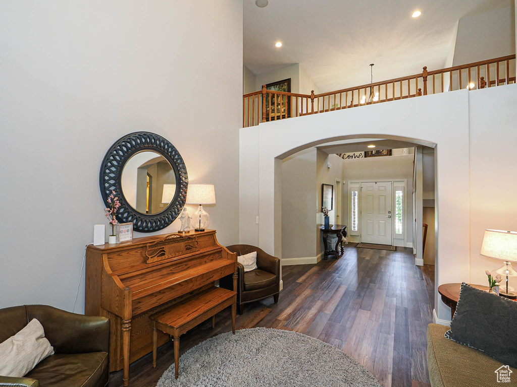 Foyer entrance with arched walkways, dark wood finished floors, baseboards, recessed lighting, and a towering ceiling