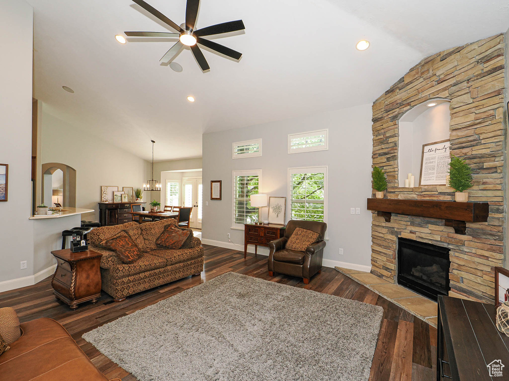 Living area with a ceiling fan, dark wood finished floors, a fireplace, baseboards, and high vaulted ceiling