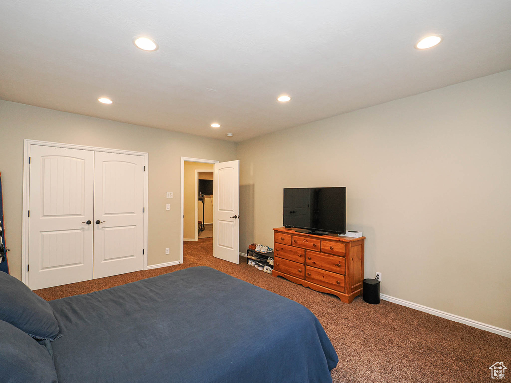 Carpeted bedroom with recessed lighting, baseboards, and a closet
