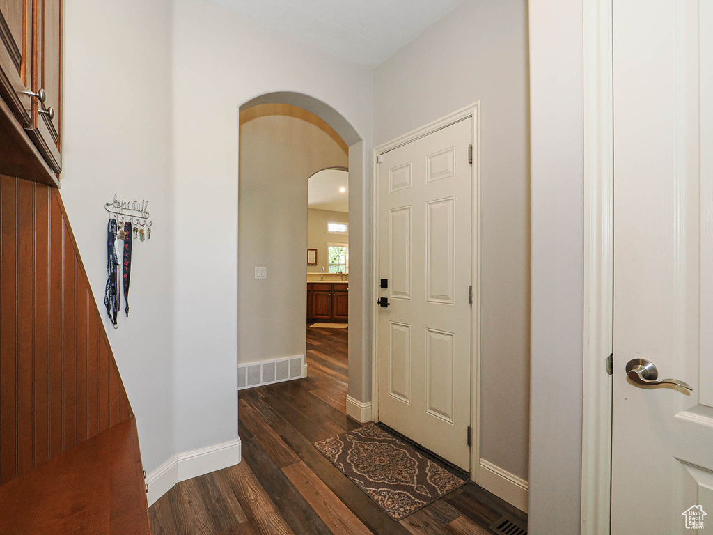 Entryway with arched walkways, dark wood finished floors, and baseboards