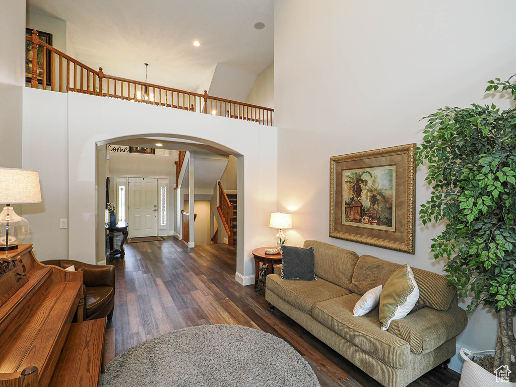 Living room with arched walkways, wood finished floors, a high ceiling, stairway, and baseboards