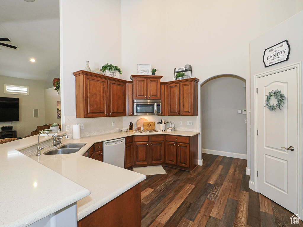 Kitchen featuring stainless steel appliances, light countertops, a peninsula, a sink, and recessed lighting