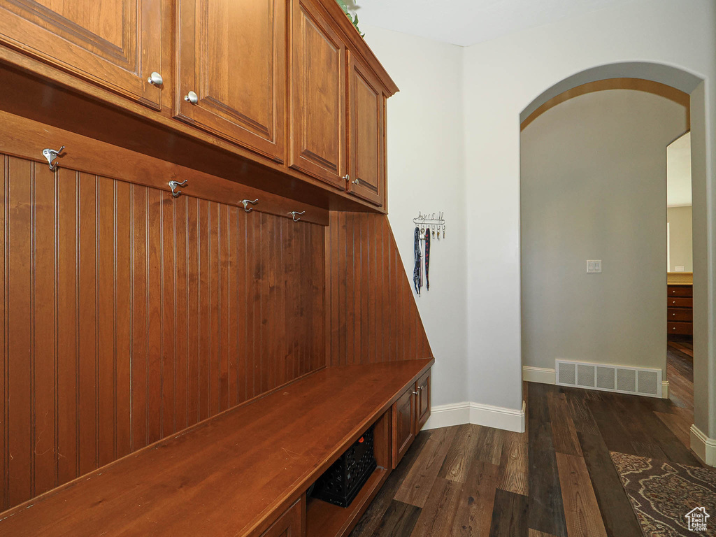 Mudroom with arched walkways, dark wood finished floors, and baseboards