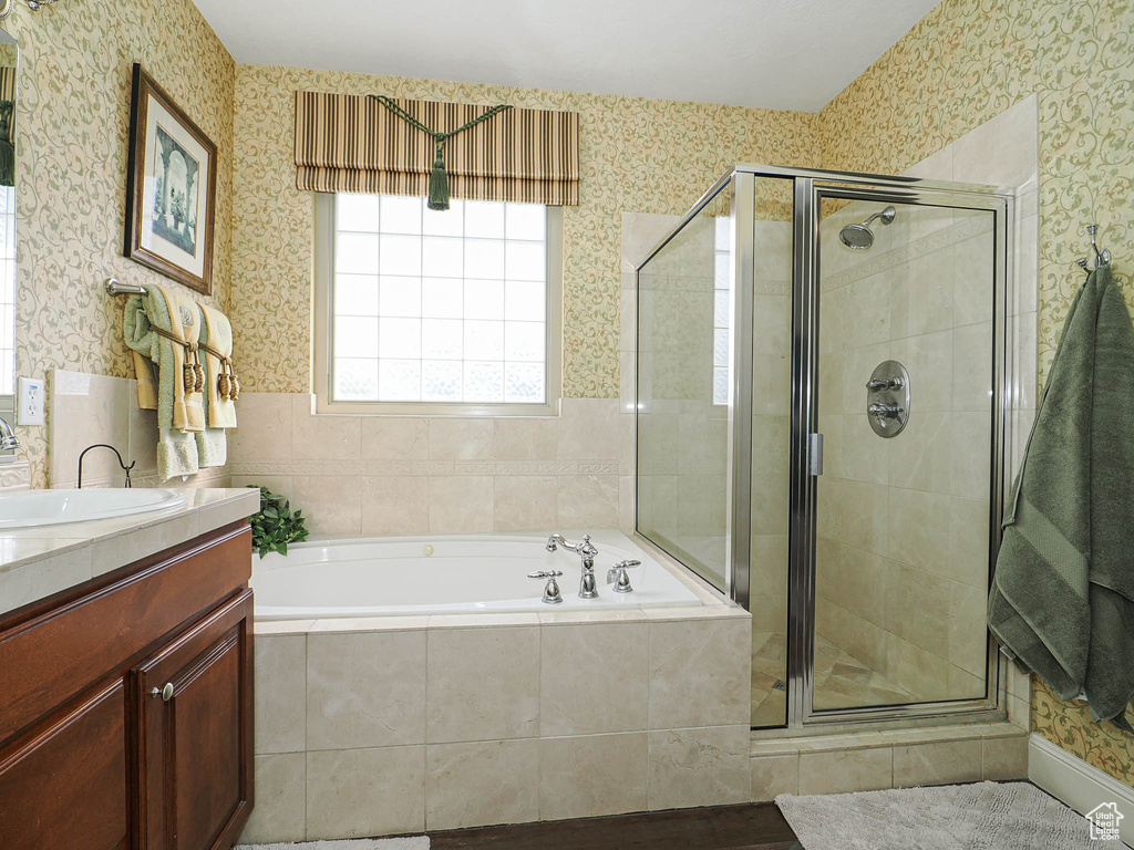 Bathroom with a bath, vanity, a stall shower, and wallpapered walls