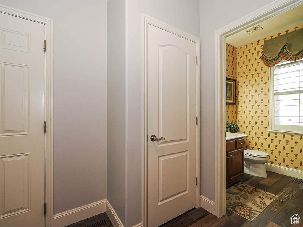 Half bath featuring vanity, baseboards, wood finished floors, and toilet