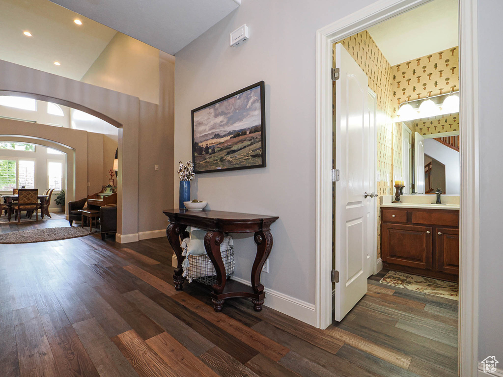 Foyer entrance featuring dark wood-style flooring, arched walkways, baseboards, and recessed lighting