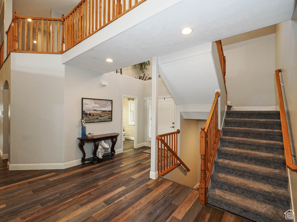 Stairway featuring wood finished floors, baseboards, recessed lighting, and a high ceiling