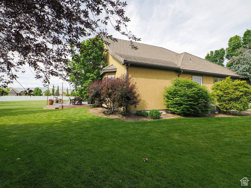 View of side of property with stucco siding, a patio area, and a tile roof