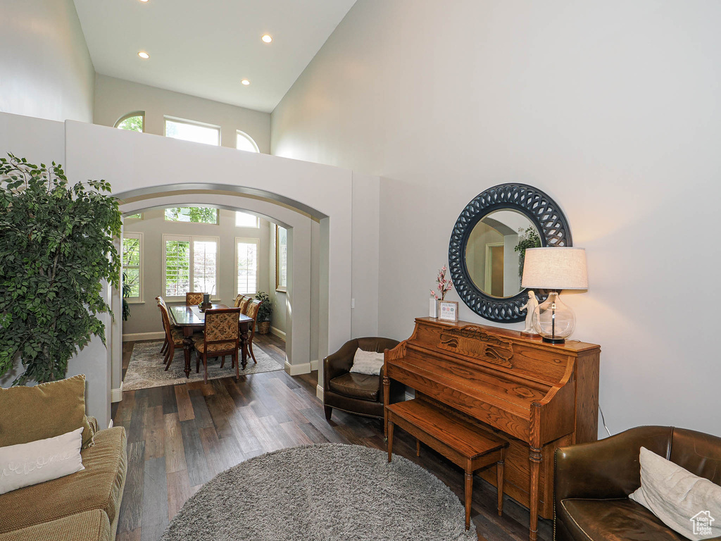 Living area featuring arched walkways, a high ceiling, recessed lighting, wood finished floors, and baseboards