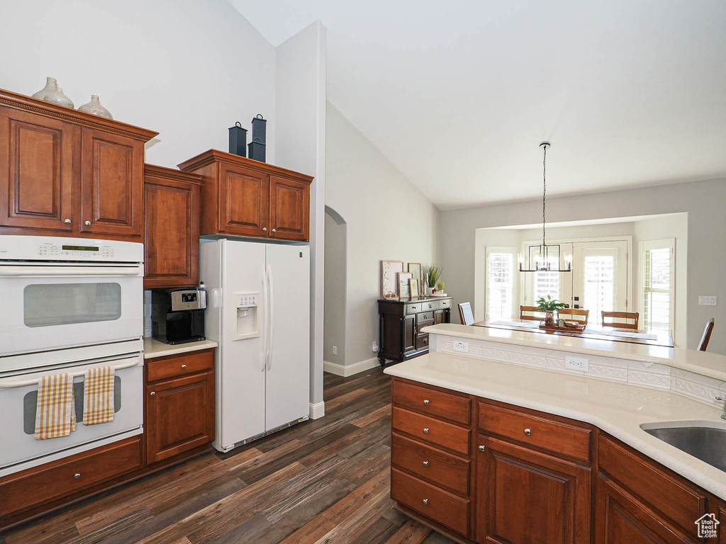 Kitchen featuring white appliances, dark wood-style floors, light countertops, and high vaulted ceiling