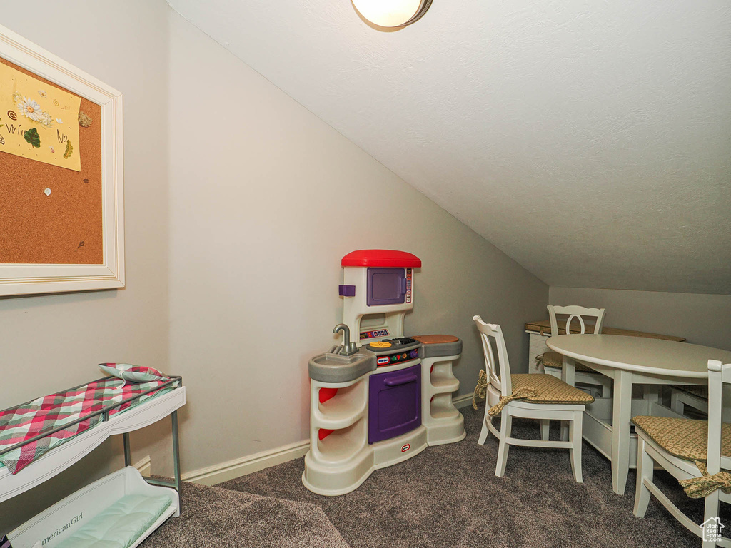 Carpeted office with vaulted ceiling and baseboards