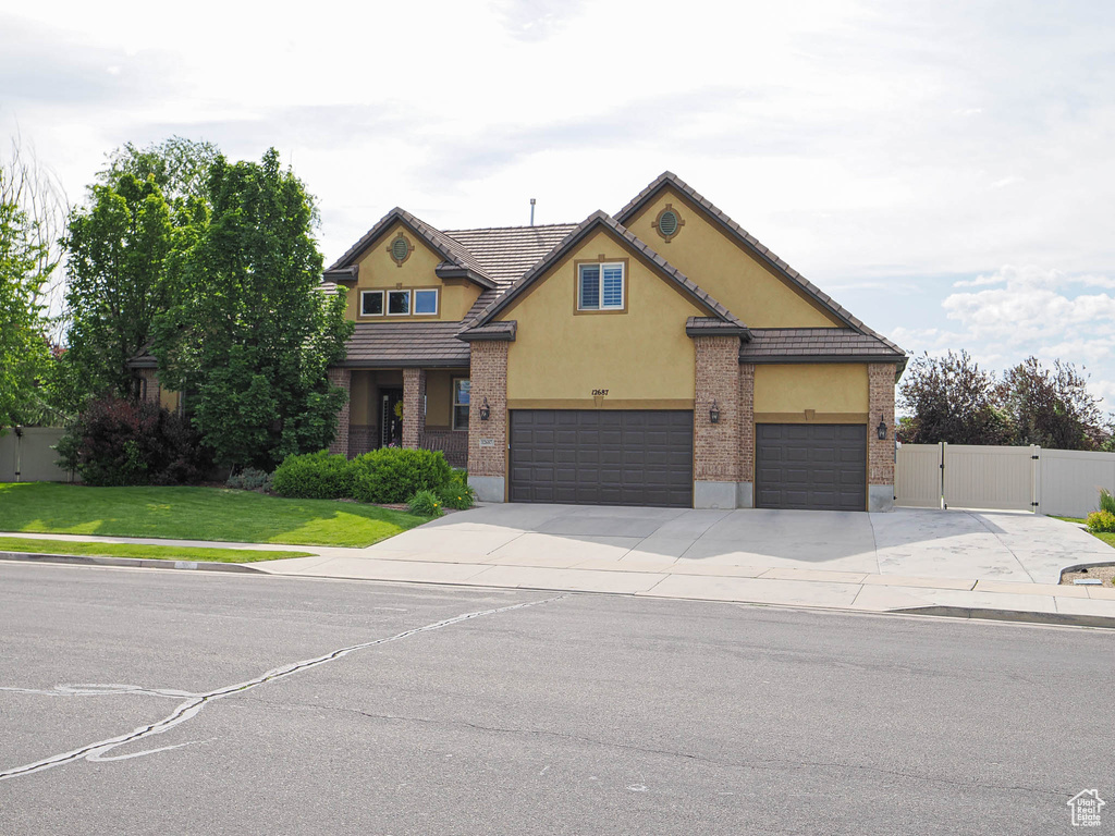 Traditional-style home featuring concrete driveway, stucco siding, a gate, an attached garage, and a tile roof