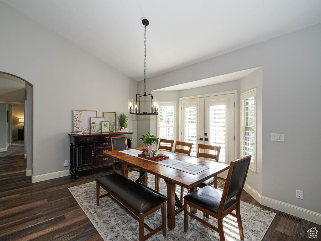 Dining room featuring arched walkways, baseboards, dark wood-style floors, lofted ceiling, and french doors