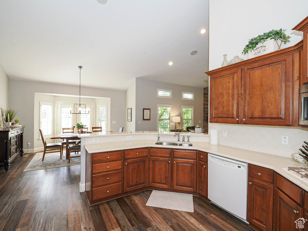 Kitchen with white appliances, a sink, a peninsula, plenty of natural light, and recessed lighting