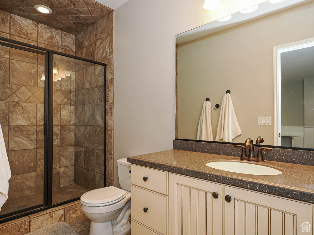 Full bath with toilet, a stall shower, and vanity