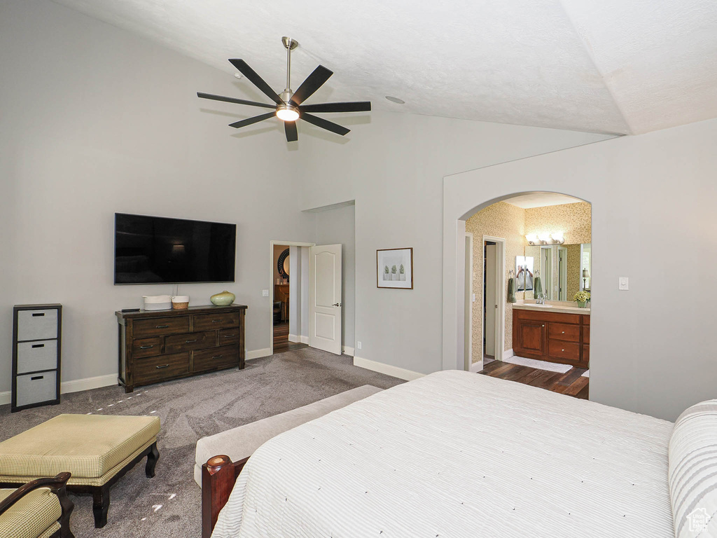 Bedroom featuring lofted ceiling, arched walkways, carpet flooring, baseboards, and a ceiling fan