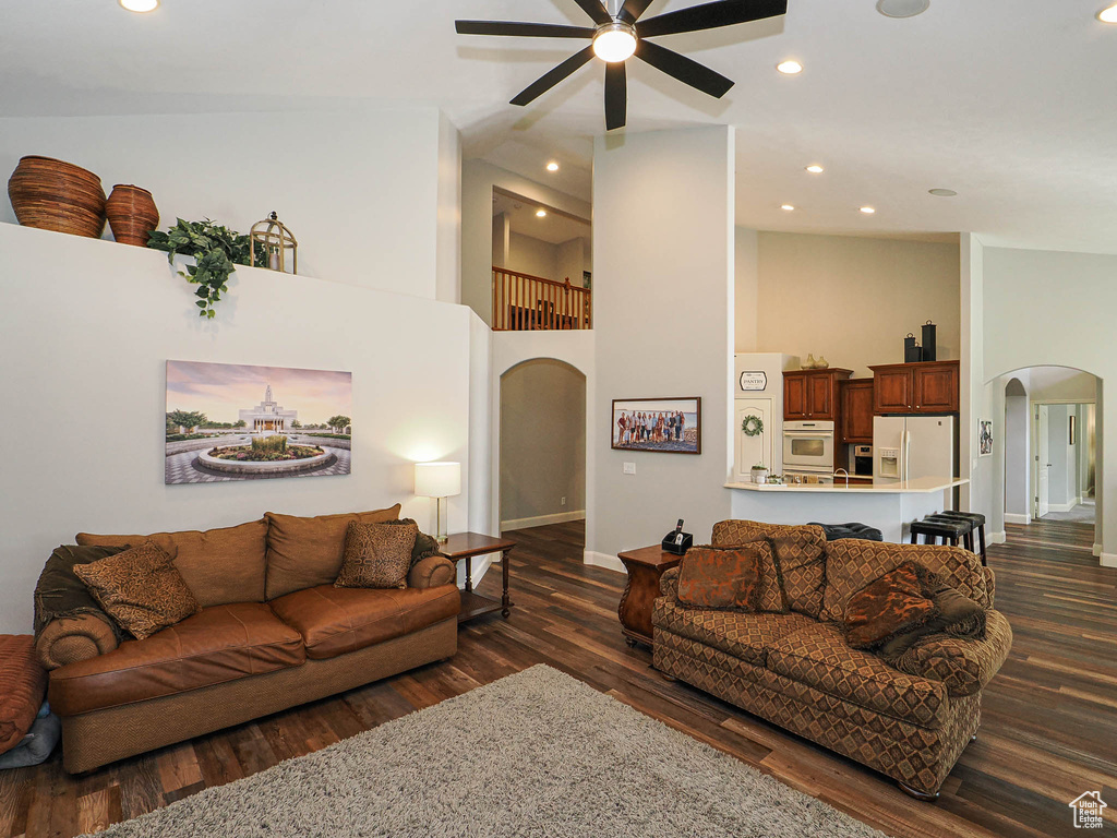 Living area featuring arched walkways, ceiling fan, dark wood finished floors, baseboards, and recessed lighting