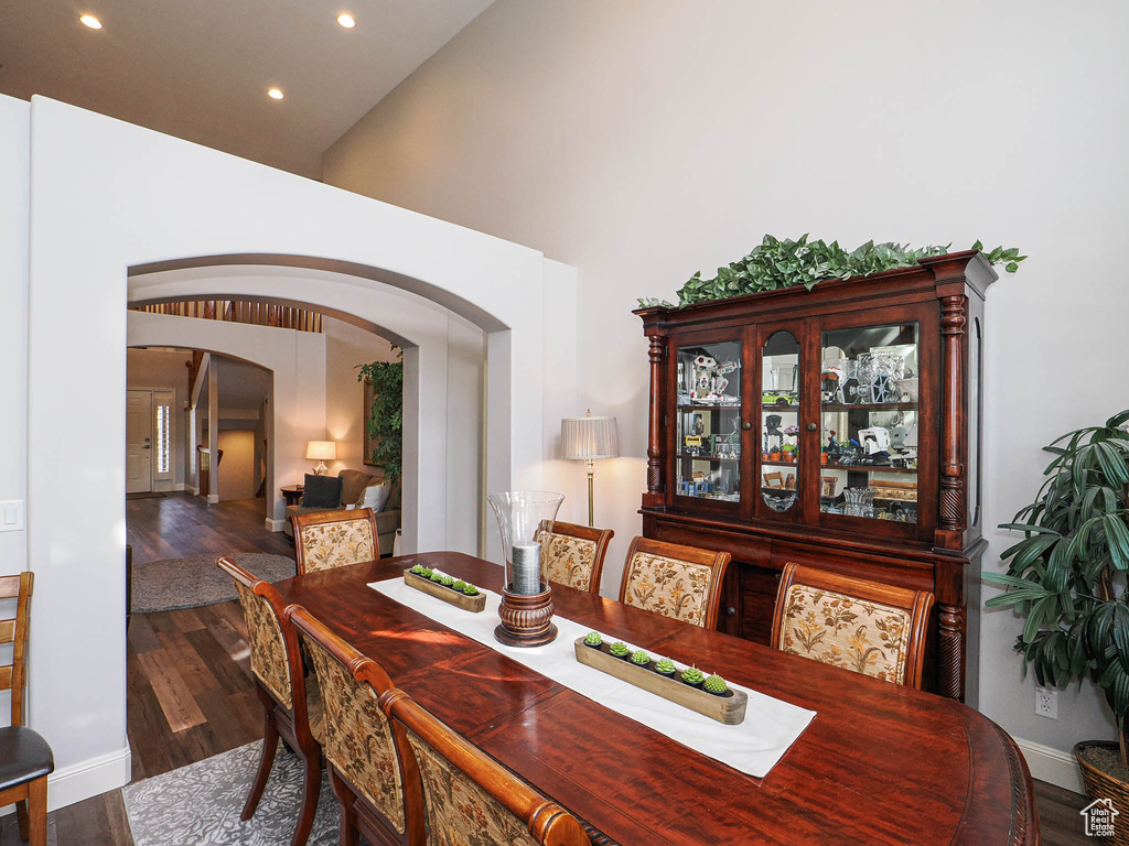 Dining area with arched walkways, recessed lighting, baseboards, wood finished floors, and a high ceiling
