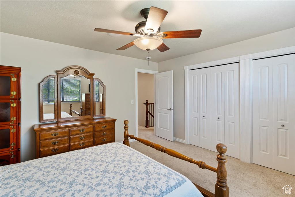 Bedroom featuring light colored carpet, multiple closets, ceiling fan, and baseboards