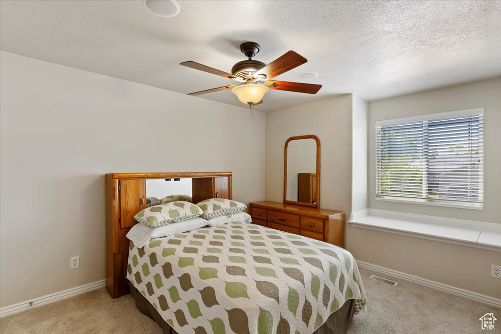 Bedroom with carpet floors, baseboards, a ceiling fan, and a textured ceiling